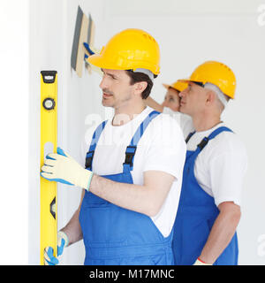 Team of workmen align wall using tools Stock Photo