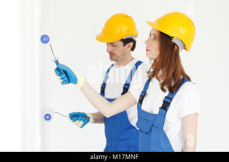 Two young workers in uniform painting the wall Stock Photo