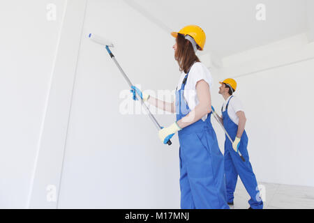 Two young workers in uniform painting the wall Stock Photo