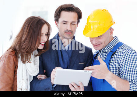 Worker and couple using tablet pc at construction site Stock Photo