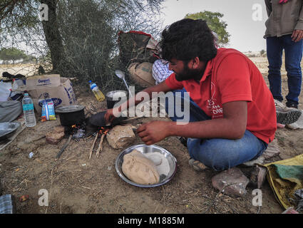 Jaisalmer, India - Mar 4, 2012. A man cooks meal during camel safari in Jaisalmer, India. Camel safaris in That desert are very popular among tourists Stock Photo