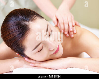 close-up of face of a beautiful young asian woman lying on front on bed receiving massage in spa salon. Stock Photo