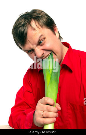 Young handsome man is biting a green leek onion on his palm. On white background. Stock Photo