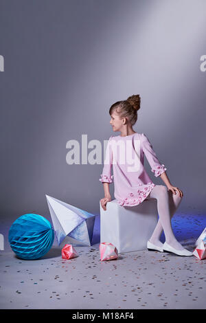 Designer collection. Origami and minimalism. Fashion children. Girl in beautiful pink dress . Fashion catalog clothes. Studio shot. Stock Photo