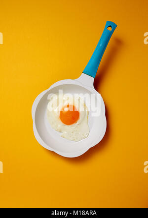 Fried egg in frying pan on colored background Stock Photo