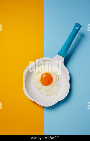 Fried egg in frying pan on colored background Stock Photo