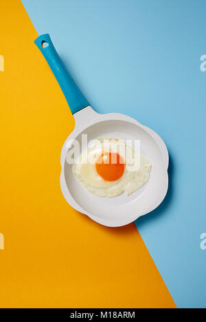 Fried egg in frying pan on colored background Stock Photo