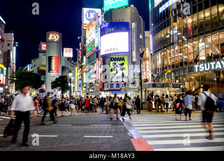 Rush hour at Tokyo's Shibuya intersection with pedestrians crossing the street and billboards and shops in the background. Stock Photo
