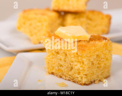 Piece of freshly baked cornbread with creamy butter on top. Stock Photo