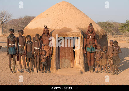 Himba women and children in front of a mud hut,Kaokoveld,Kunene,Namibia Stock Photo