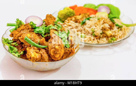 Vegetable fried rice and spicy chicken kosha - Popular Bengali Indian food isolated on white background. Stock Photo