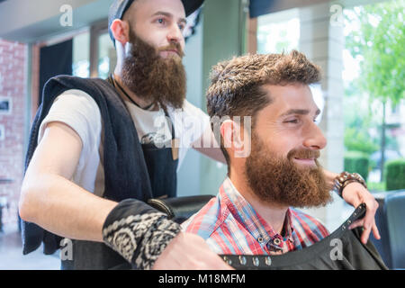 Handsome young bearded man smiling before having a trendy haircu Stock Photo
