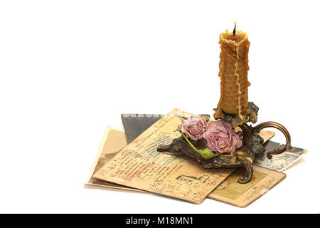 Antique bronze candlestick, burning candle, roses, old photos and correspondence isolated on white background Stock Photo