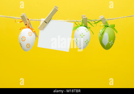 Easter eggs decoration. Eggs hanging on yellow background with blank card Stock Photo