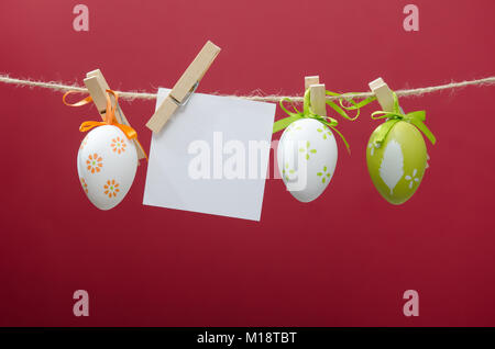 Easter eggs decoration. Eggs hanging on red background with blank card Stock Photo