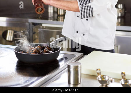 Chef peppering oven-steamed mussels in pan. Stock Photo