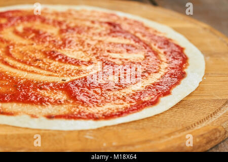 Close up smeared pizza crust with red sauce. Stock Photo