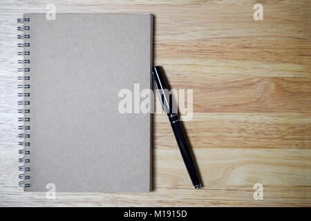 blank spiral notebook and black pen on wood background Stock Photo