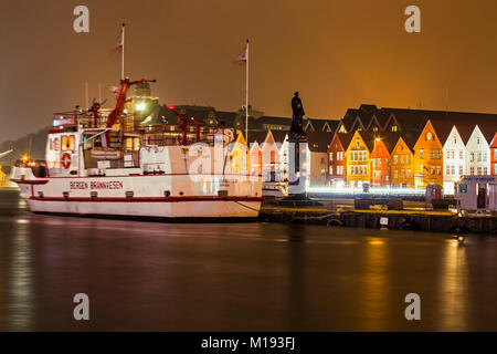 City Fire Department ship & statue of WWII naval hero Leif Andreas Larsen on historic Bryggen waterfront at night. Bergen, Hordaland, Norway. Stock Photo