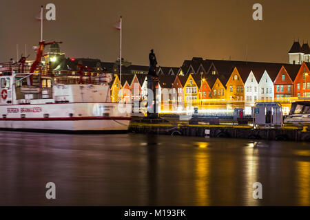 City Fire Department ship & statue of WWII naval hero Leif Andreas Larsen, historic Bryggen waterfront at night. Bergen, Hordaland, Norway. Stock Photo