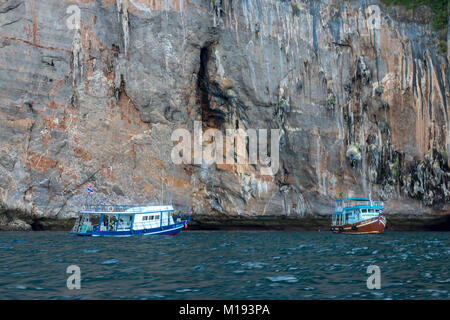 Phi Phi Island Krabi Thailand January 30, 2016 Dive boats, dwarfed by the sheer cliffs of Koh Phi Phi Lee. Stock Photo
