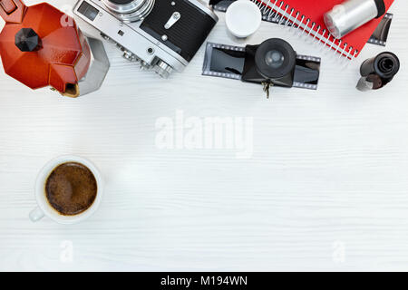 red coffee pot with a cup, vintage photo camera, negative films, red notebook on white wooden background Stock Photo
