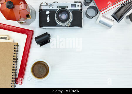 retro camera, grunge coffee pot, red photo frame and notebook on white wooden background flat view Stock Photo
