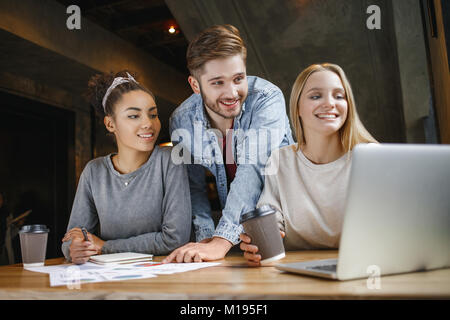 Young women and man students having a business lunch browsing laptop looking for creative ideas smiling cheerful working on project Stock Photo