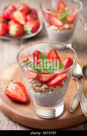 diet healthy breakfast. chia pudding, strawberries and muesli in a glass , fresh strawberry on  old wooden background Stock Photo