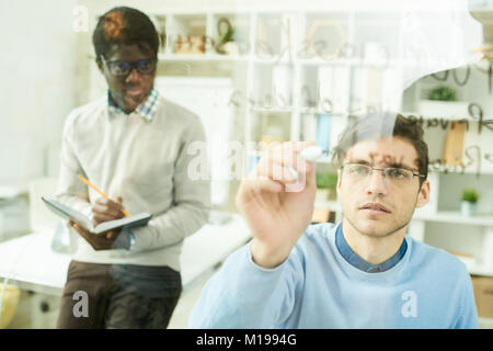 IT Developers Writing on Glass Wall Stock Photo