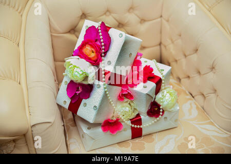 White and pink roses and white pearls on top. Two white engagement boxes on top of the armchair. Stock Photo