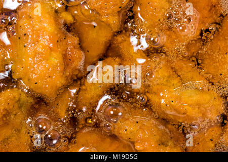 Frying the meat wrapped in breadcrumb on the pan, close up. Fried chicken in oil. Stock Photo