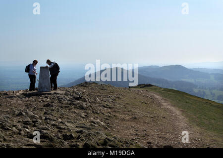 Malvern, UK - 29th March 2012: Two women examine the old trig point on Worcester Beacon on top of the Malvern Hills, Worcestershire, UK. Worcestershire Beacon, also known as Worcester Beacon is a hill whose summit at 425 m (1,395 ft) is the highest point of the range. Stock Photo