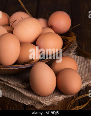 Brown chicken eggs on a burlap cloth and in a bowl in background Stock Photo