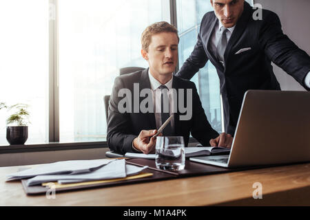 Corporate professionals working together on laptop. Two businessmen in office discussing business plan. Stock Photo