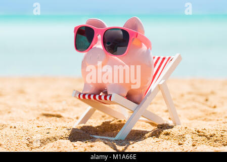 Pink Piggy Bank With Sunglasses On The Small Deck Chair At Beach Stock Photo