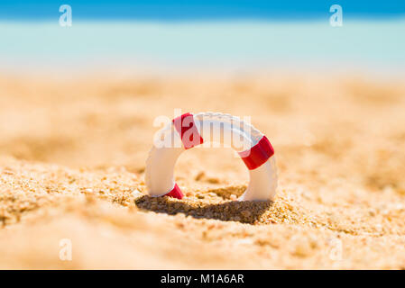 Miniature White And Red Lifebuoy In Sand At Beach Stock Photo