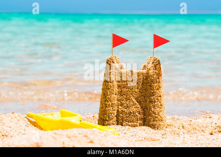 Red Flags On Sandcastle Made Near The Coast At Beach Stock Photo