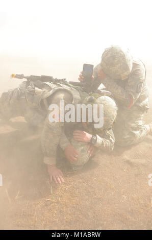 Spc. Taylor Walker, left, a field medic with Headquarters, 1st Squadron, 18th Cavalry, and a San Diego Police Officer and Spc. Juan Perez, right, from Ontario, cover and block Spc. Cesire Martinez, who is from San Bernardino, from a sea of dirt and dust. Perez and Martinez are assigned to D Co., 40th Brigade Support Battalion and are helping and role playing as litter patient and carrier. The training, being held at Fort Hunter Liggett, was designed to familiarize everyone on how to call in a medevac, prepare and load littered patients onto a waiting helicopter, operated by 3rd Battalion, 140t Stock Photo