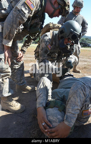 Spc. Brad Machado, center, a crew chief and flight medic on a 3rd Battalion, 140th Aviation Battalion Security and Support UH-60 Black Hawk, checks on the bandage put in place by Spc. Taylor Walker, left, a field medic with Headquarters, 1st Squadron, 18th Cavalry, and a San Diego Police Officer. Both medics are learning from each other during the California Army National Guard's annual training, June 6-20, 2015, while using Soldiers like Spc. Juan Perez, right, from Ontario, and Spc. Cesire Martinez, lying down, from San Bernardino, both assigned to D Co., 40th Brigade Support Battalion, help Stock Photo