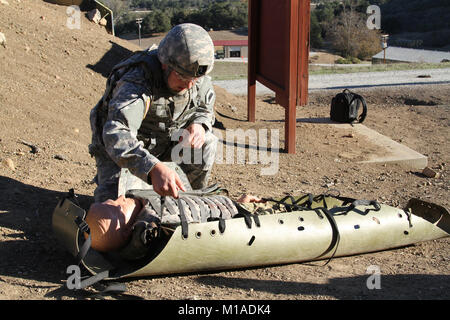 Staff Sgt. Miguel Ramirez II, Headquarters Detachment, Joint Forces Headquarters, straps a mannequin simulating an injured Soldier to a skid during the Nov. 19 React to Contact portion of the California Army National Guard’s 2015 Best Warrior Competition at Camp San Luis Obispo, San Luis Obispo, California. (U.S. Army National Guard photo/Staff Sgt. Eddie Siguenza) Stock Photo