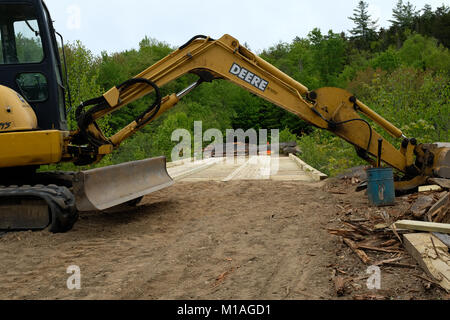 John Deere track hoe excavator working to replace a logging truck bridge in the Adirondack wilderness. Stock Photo