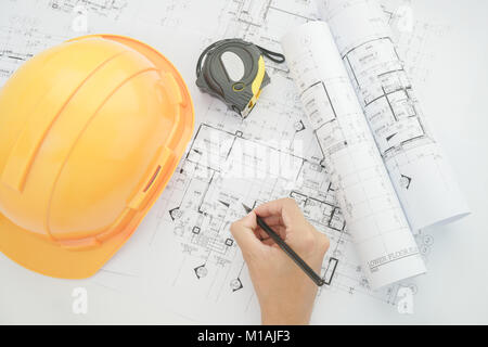 Architect working on construction blueprint. Architects workplace - architectural project, blueprints, helmet, measuring tape, Construction concept. E Stock Photo