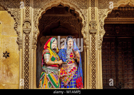Rajasthani women in traditional dresses and jewelery pose at Patwon Ki Haveli Jaisalmer, Rajasthan. Stock Photo