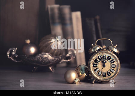 Vintage alarm clock showing five to twelve among old books in a study room. Space for your greeting. Happy New Year 2017! Stock Photo