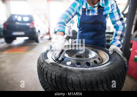 Female mechanic repairing a car in a garage. Stock Photo