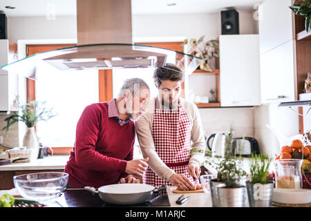 Hipster son with his senior father cooking in the kitchen. Stock Photo
