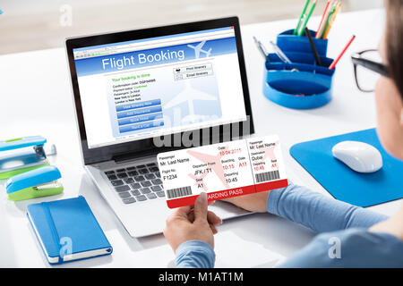 Close-up Of A Woman Holding Airline Ticket In Hand Booking Flight On Laptop Stock Photo