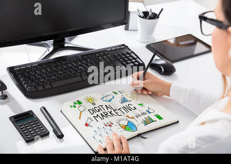 Close-up Of A Businesswoman Drawing Digital Marketing Chart On Notebook In Office