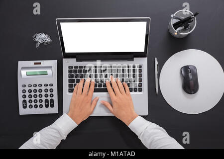 Close-up Of A Businesswoman Tying On Laptop Over The Desk Stock Photo